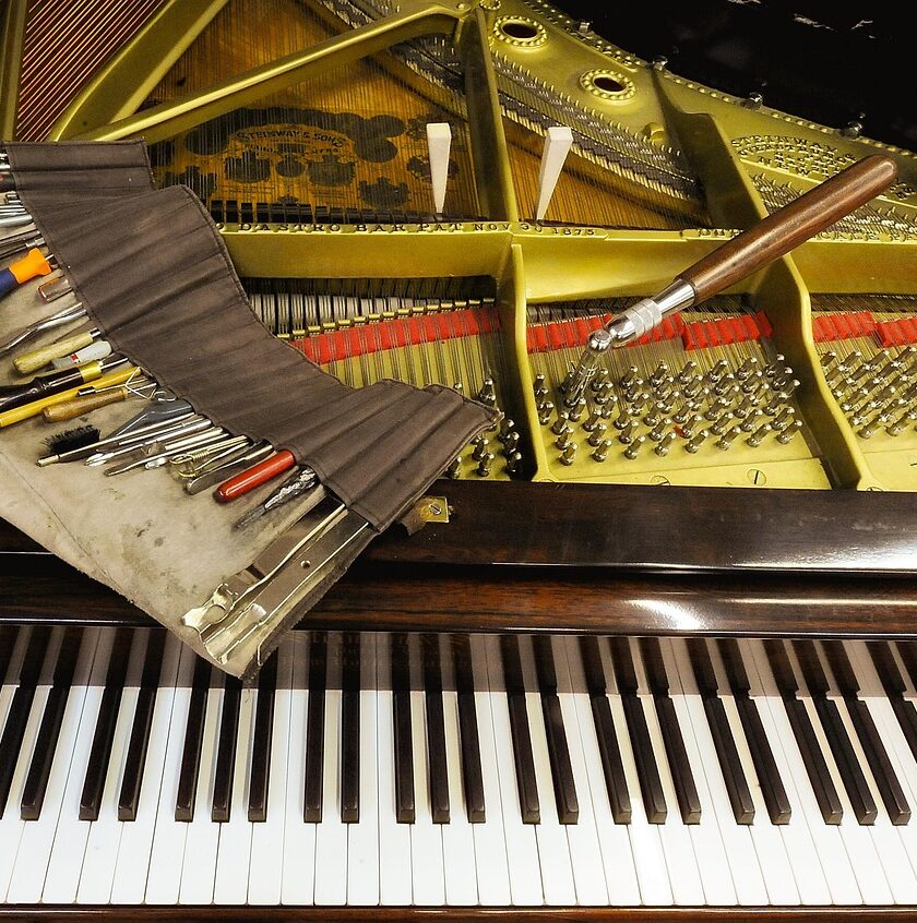 Inside of grand piano with tuning hammer and other tools